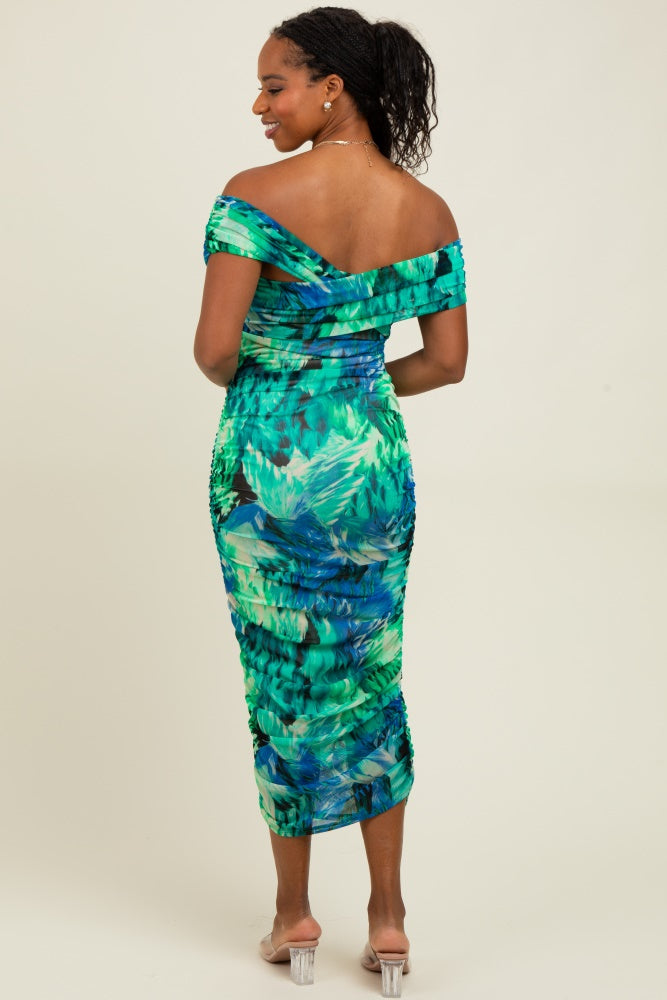 woman wearing a tropical print off-the-shoulder midi dress with ruching and a fitted silhouette