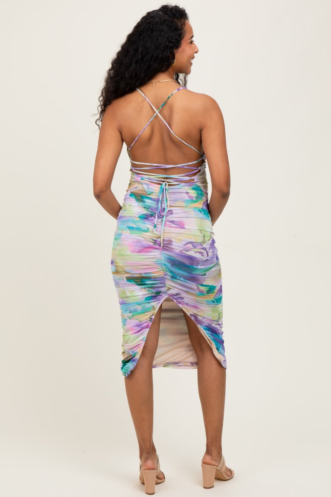 woman wearing a colorful abstract print maternity dress with crisscross straps and a side slit, showing a baby bump