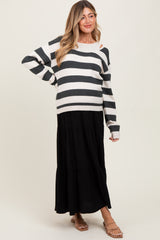 woman wearing a black and white striped maternity sweater with an open shoulder, paired with a black tiered maxi skirt