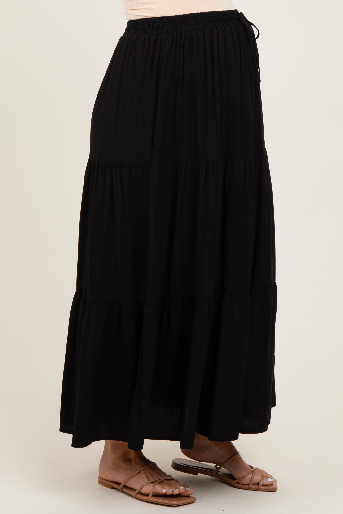woman wearing a black tiered maxi skirt, designed for maternity wear, styled with flat sandals