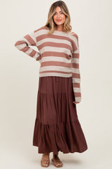 woman wearing a striped brown and beige maternity sweater with a brown tiered maxi skirt and a visible baby bump