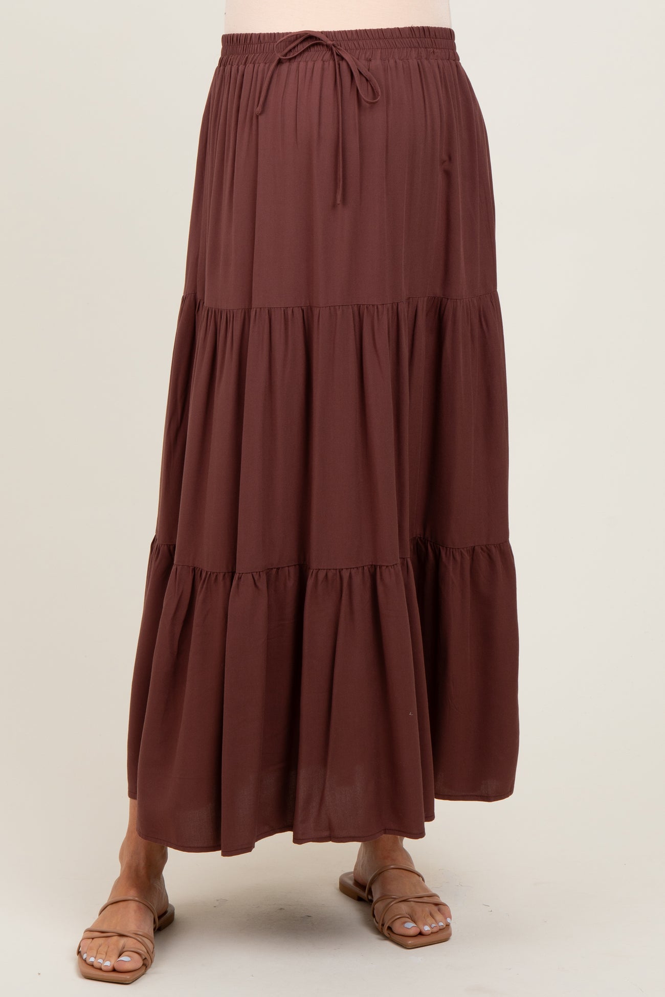 woman wearing a brown tiered maternity maxi skirt with an elastic waistband and drawstring detail