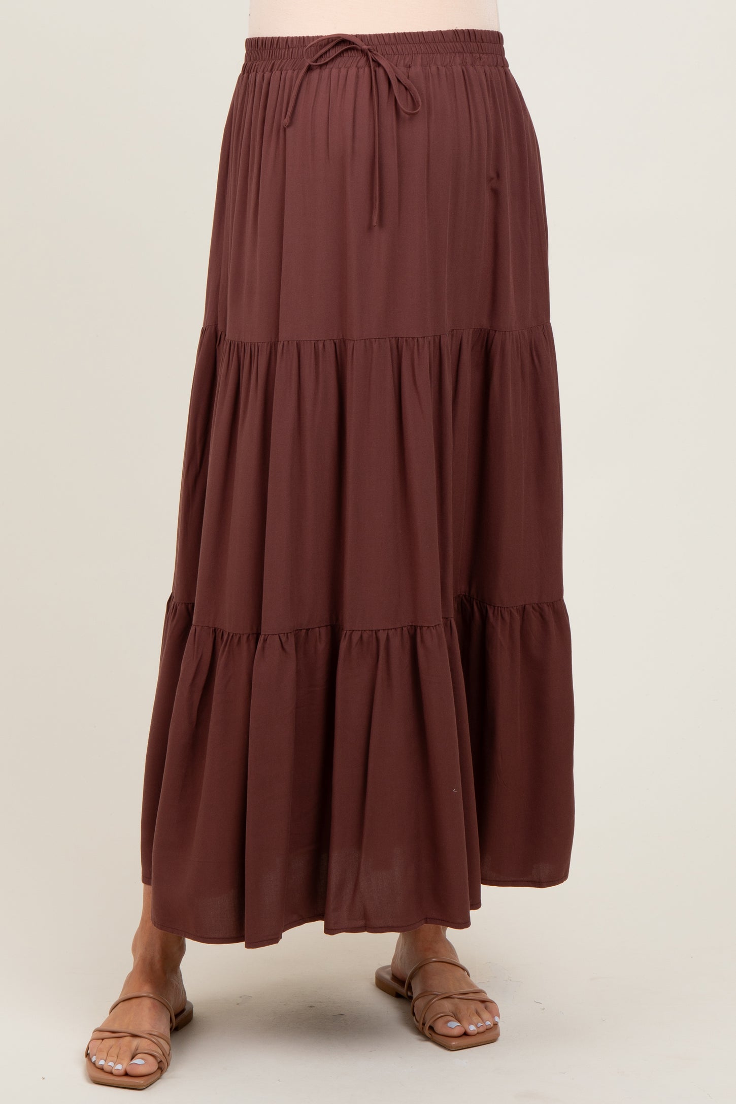 woman wearing a brown tiered maternity maxi skirt with an elastic waistband and drawstring detail