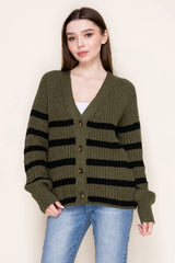 woman wearing an olive green and black striped cardigan with buttons, paired with light blue jeans