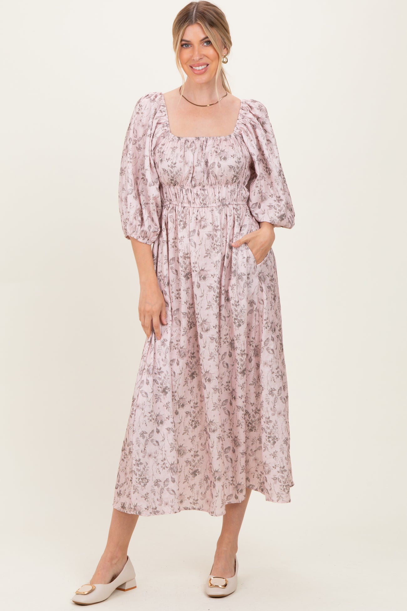 woman wearing a pink floral midi dress with puff sleeves and side pockets