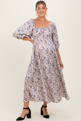 woman wearing a purple floral maxi maternity dress with puff sleeves and a visible baby bump