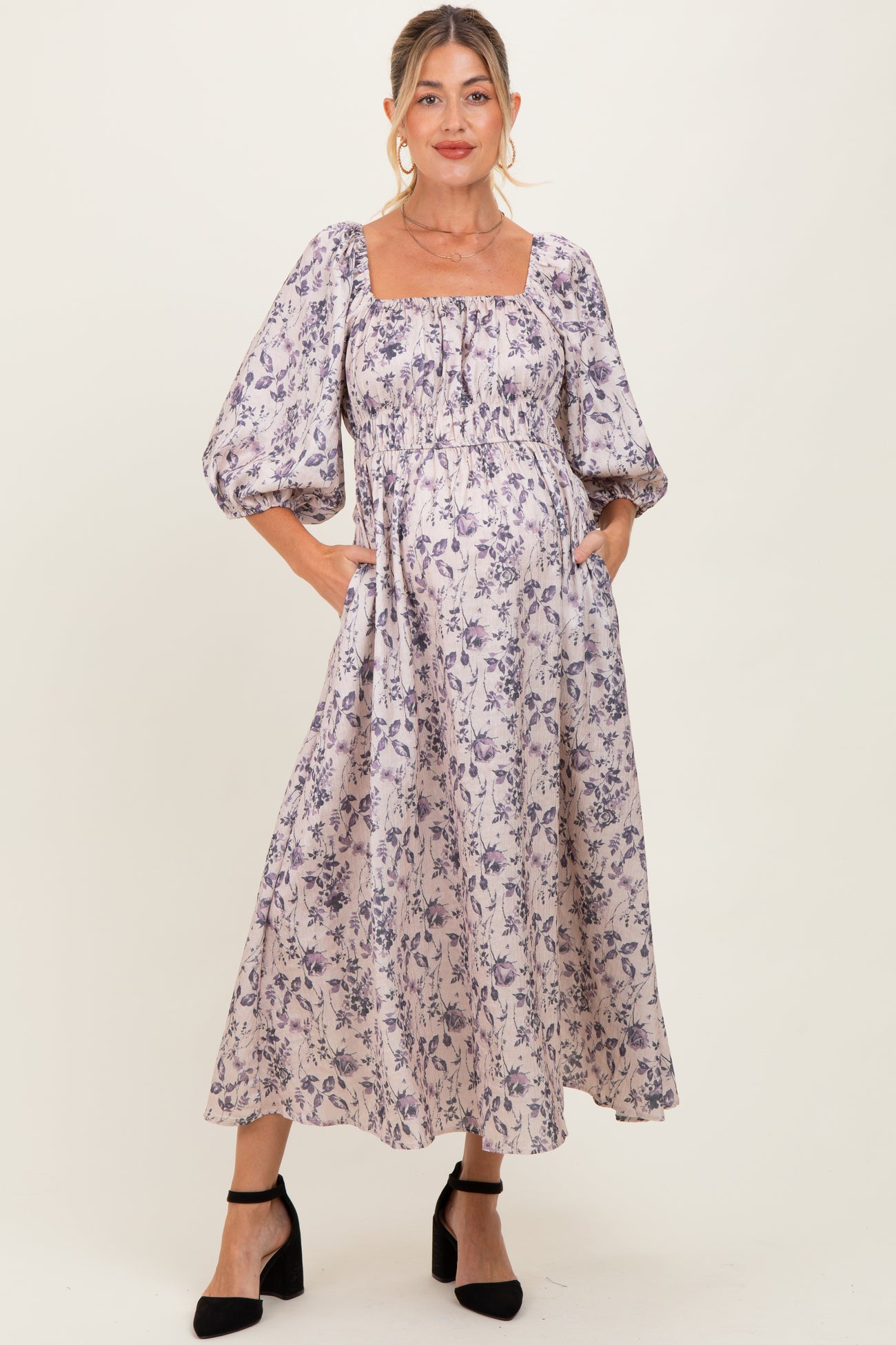woman wearing a floral print maternity dress with puff sleeves and a square neckline, highlighting her baby bump