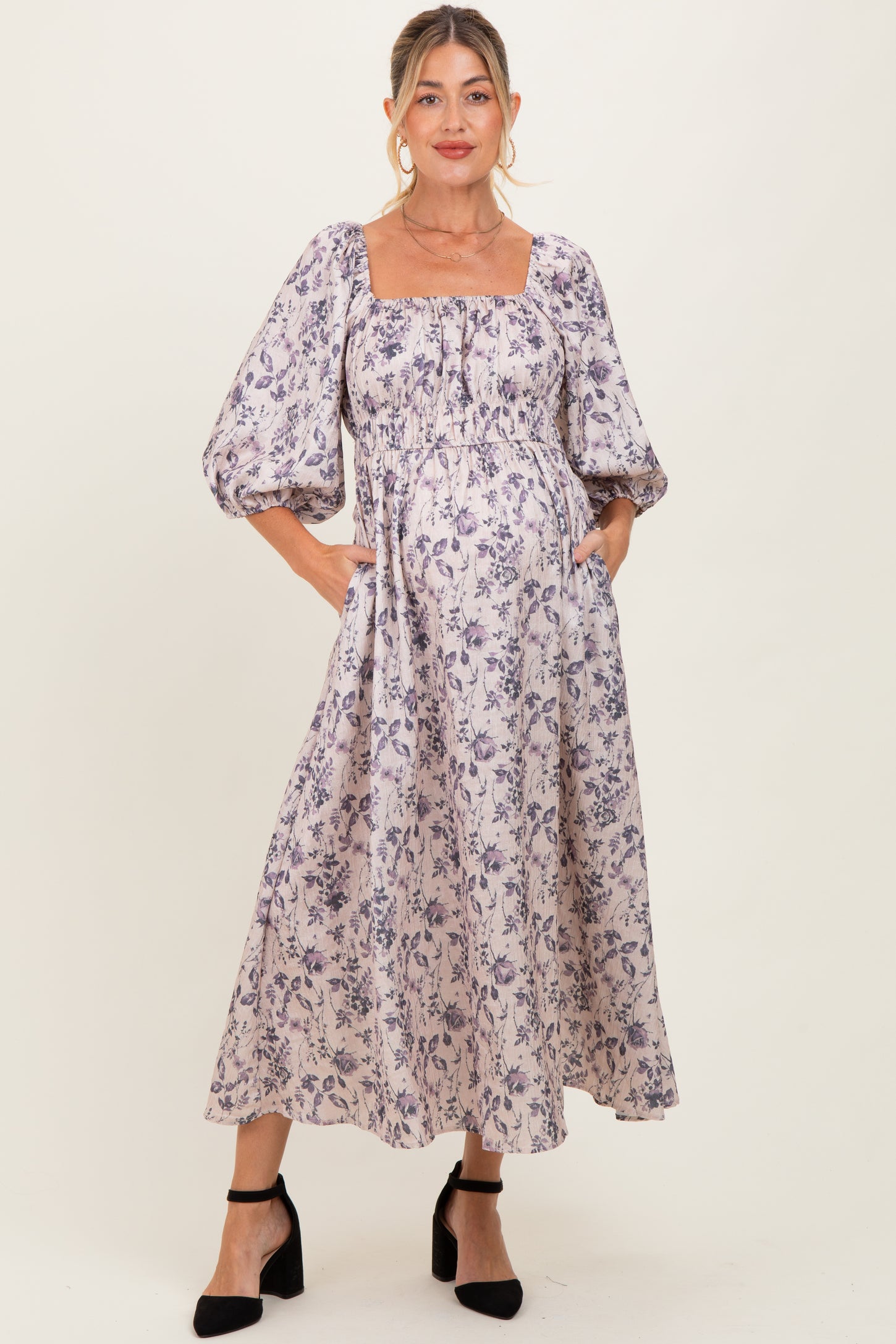 woman wearing a floral print maternity dress with puff sleeves and a square neckline, highlighting her baby bump