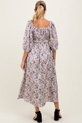 woman wearing a floral print maternity maxi dress with puffed sleeves, showing a comfortable fit around the baby bump
