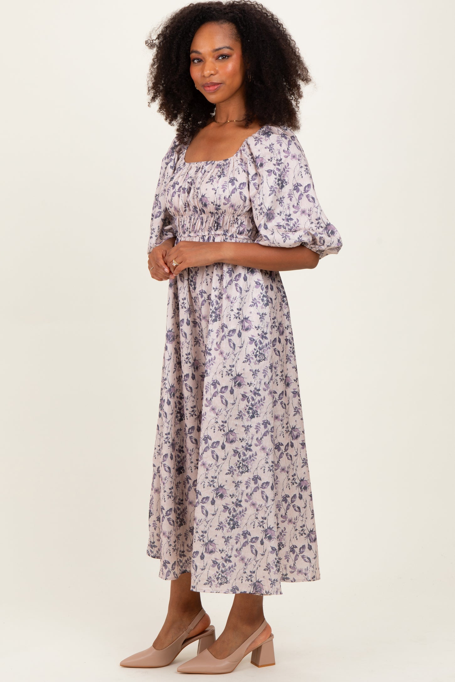 woman wearing a lavender floral midi dress with puff sleeves and a square neckline, standing in a relaxed pose