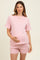 woman wearing a light pink ribbed maternity short set, showing her baby bump and smiling