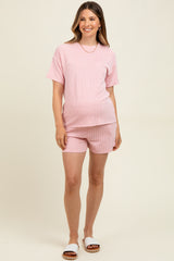 woman wearing a pink and white striped maternity loungewear set with short sleeves and matching shorts, showcasing her baby bump