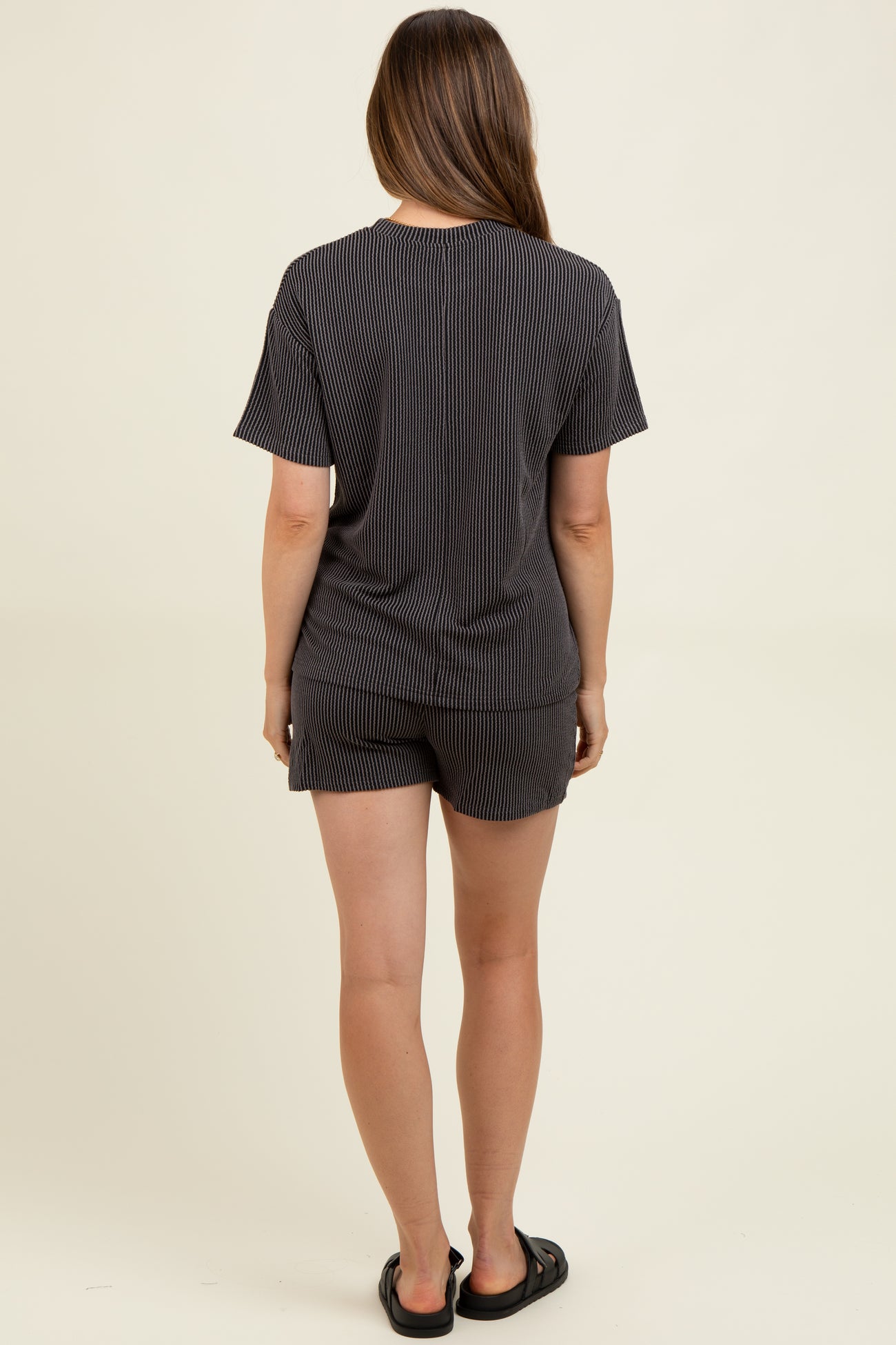 woman wearing a black and white striped maternity loungewear set with a short sleeve top and shorts, showing her back