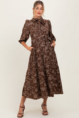 woman wearing a brown floral printed maternity dress with puff sleeves and pockets, styled with heels