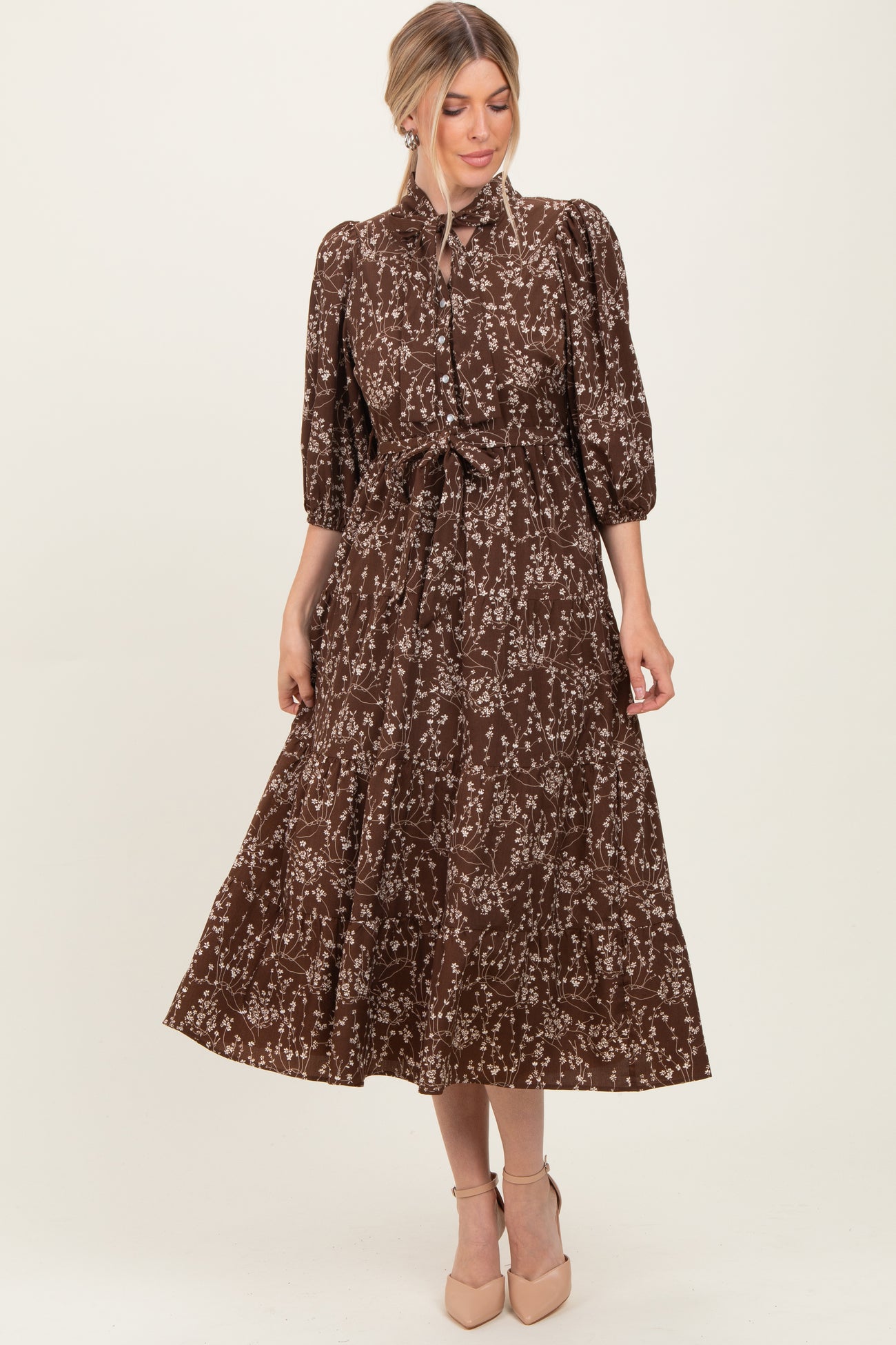 woman wearing a brown floral midi dress with puffed sleeves and tie waist detail