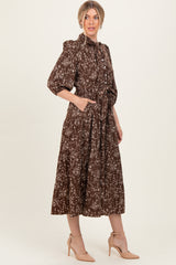 woman wearing a brown floral midi dress with a collar, long sleeves, and pockets, styled with nude heels