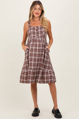 woman wearing a brown and white plaid maternity dress with pockets and a tiered skirt
