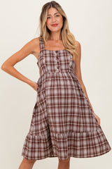 woman wearing a brown and white checkered maternity dress with spaghetti straps and a tiered hemline