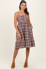 woman wearing a brown plaid midi dress with adjustable straps and pockets