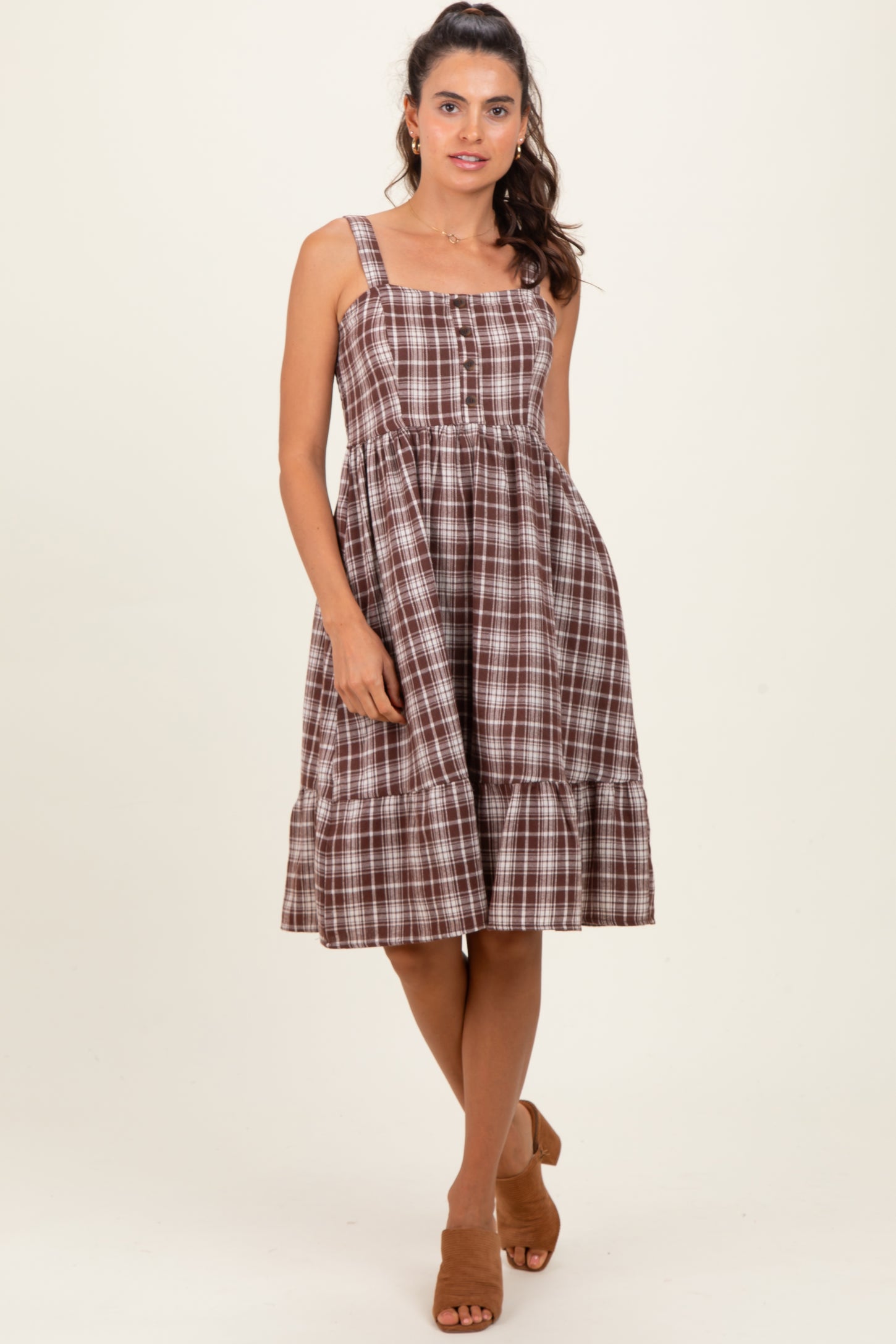 woman wearing a brown and white plaid midi dress with a square neckline and tiered ruffle hem