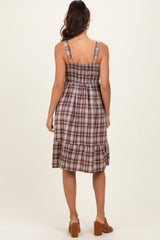 woman wearing a brown plaid smock dress with adjustable straps and a tiered skirt, viewed from the back