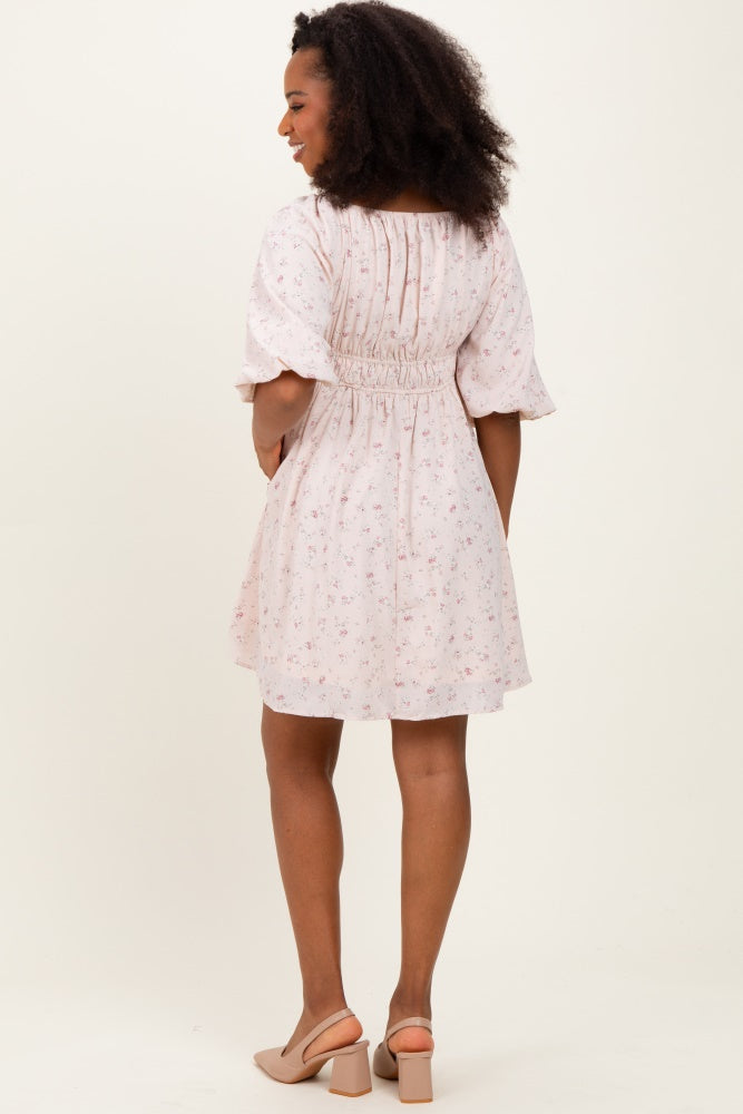woman wearing a light pink floral off-the-shoulder dress with short puff sleeves and a smocked back
