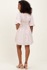 woman wearing a light pink floral off-the-shoulder dress with short puff sleeves and a smocked back