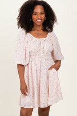 woman wearing a light pink floral short sleeve dress with a gathered waist and pockets