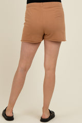woman wearing tan maternity shorts with an elastic waistband, standing with her back to the camera