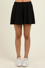 woman wearing a black pleated skater skirt with an elastic waistband and white sneakers