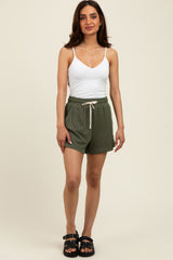 woman wearing a white tank top and olive green striped shorts with a drawstring waist and black sandals