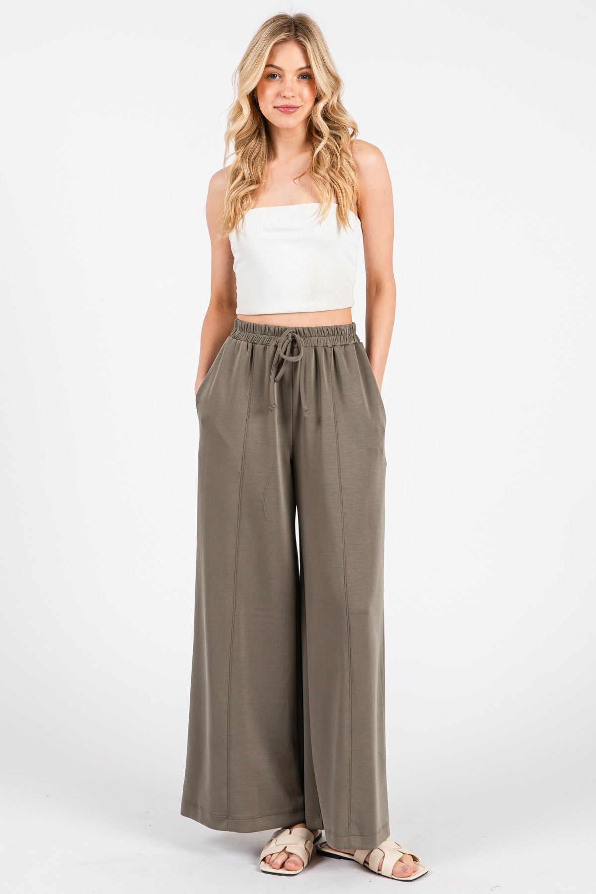 woman wearing a white cropped tank top and olive green wide-leg pants with a drawstring waist and pockets