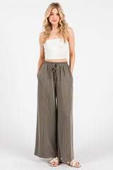 woman wearing a white cropped tank top and olive green wide-leg pants with a drawstring waist and pockets