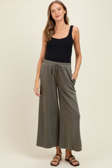 woman wearing a black tank top and olive green wide-leg maternity pants with pockets