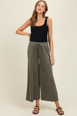 woman wearing a black tank top and olive green maternity wide-leg pants with an elastic waistband