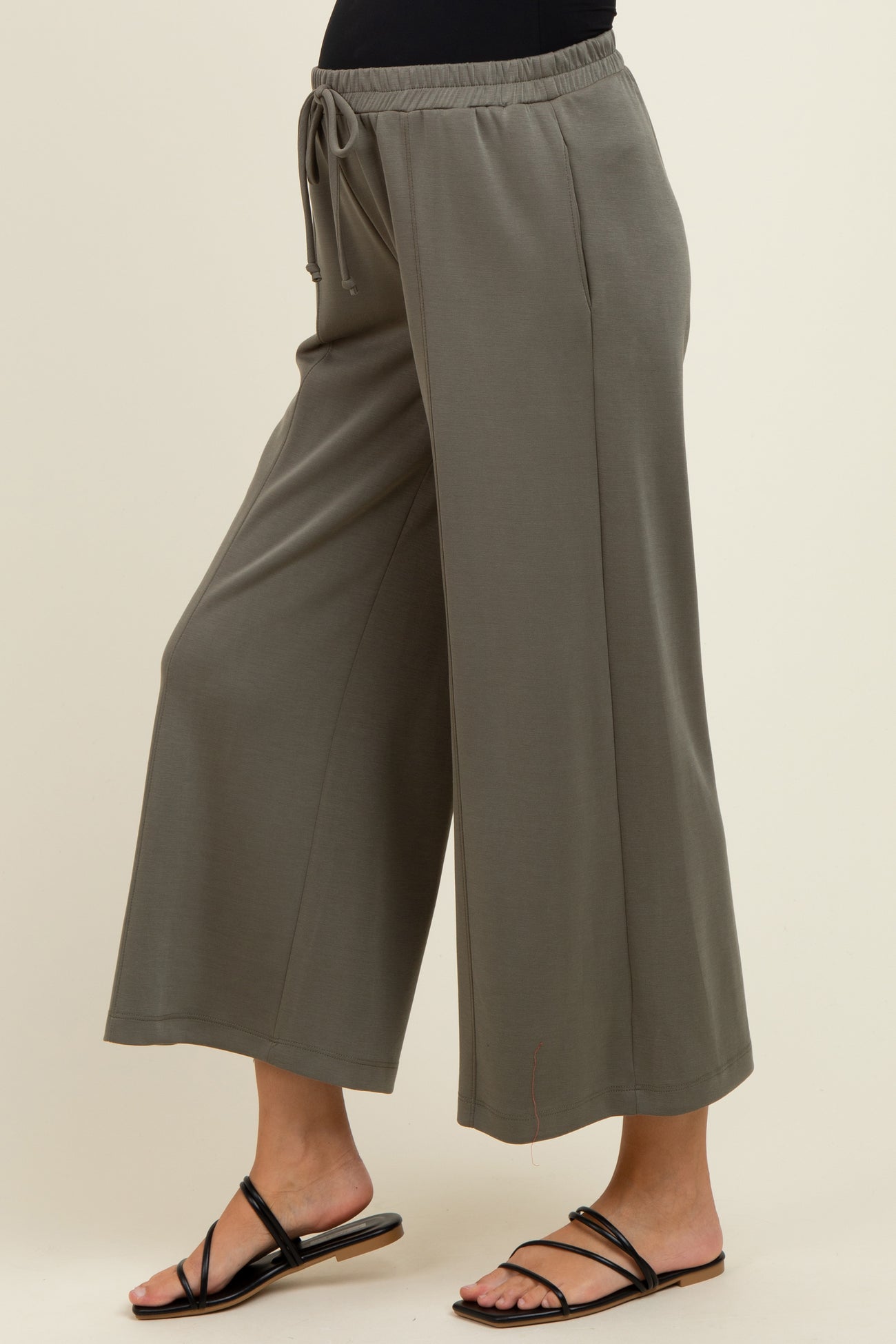 maternity wear in olive green wide leg pants with adjustable drawstring waist, model standing sideways