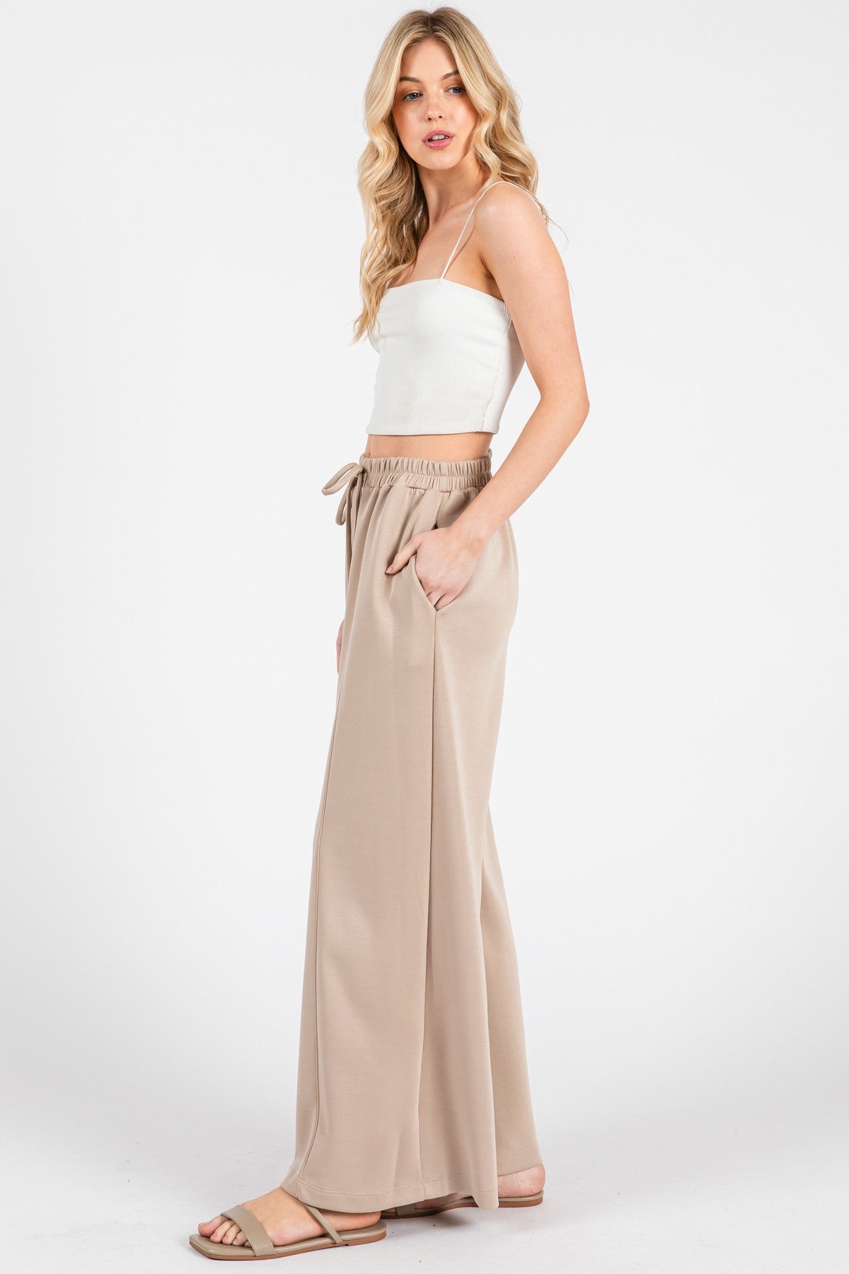 woman wearing a white ribbed crop top and beige wide-leg pants with an elastic waistband and side pockets
