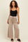 woman wearing a black maternity tank top and beige wide-leg maternity pants with an elastic waistband