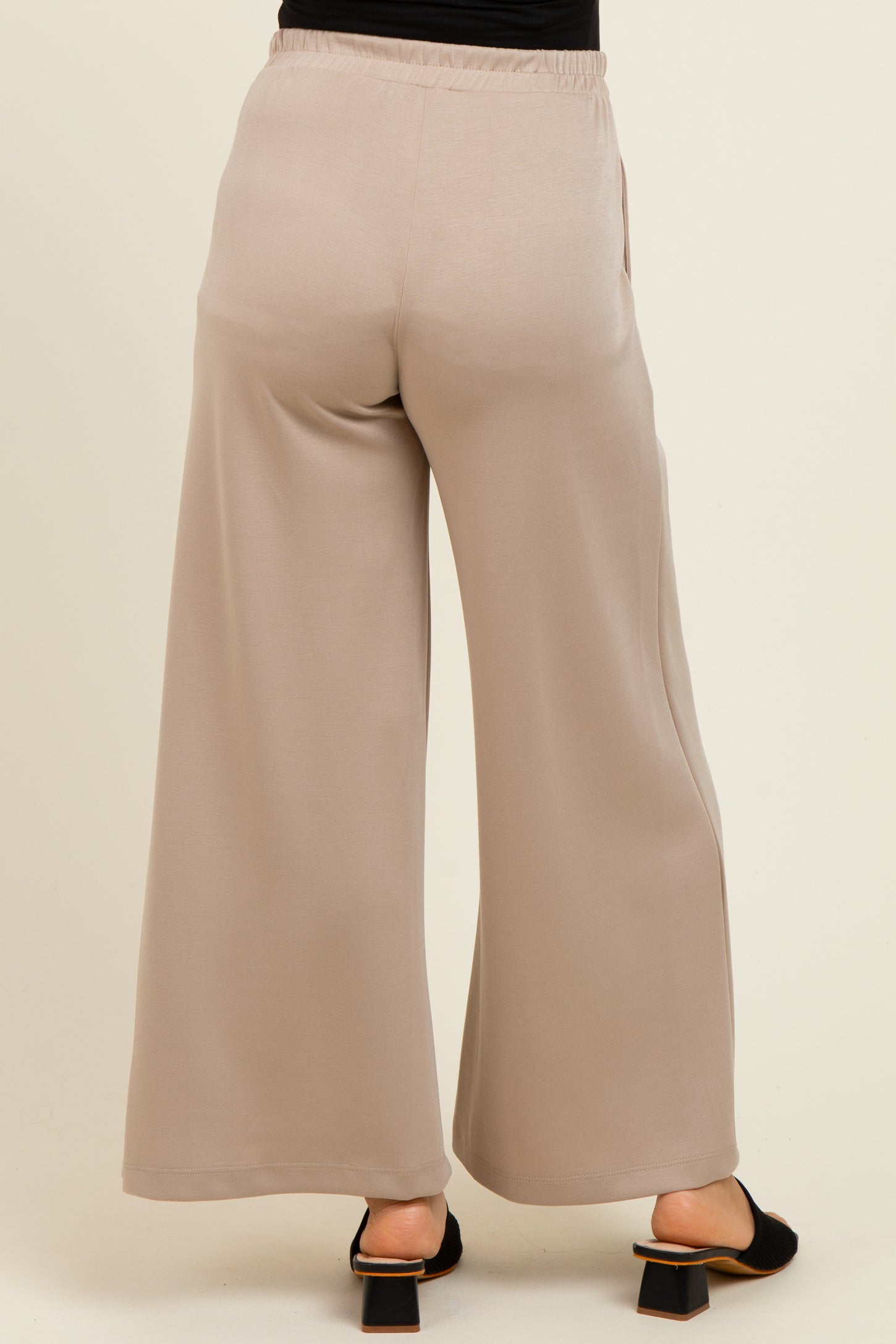 woman wearing beige maternity wide-leg pants with an elastic waistband, viewed from the back