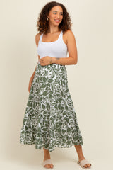 woman wearing a white tank top and a green floral print maternity maxi skirt, baby bump visible