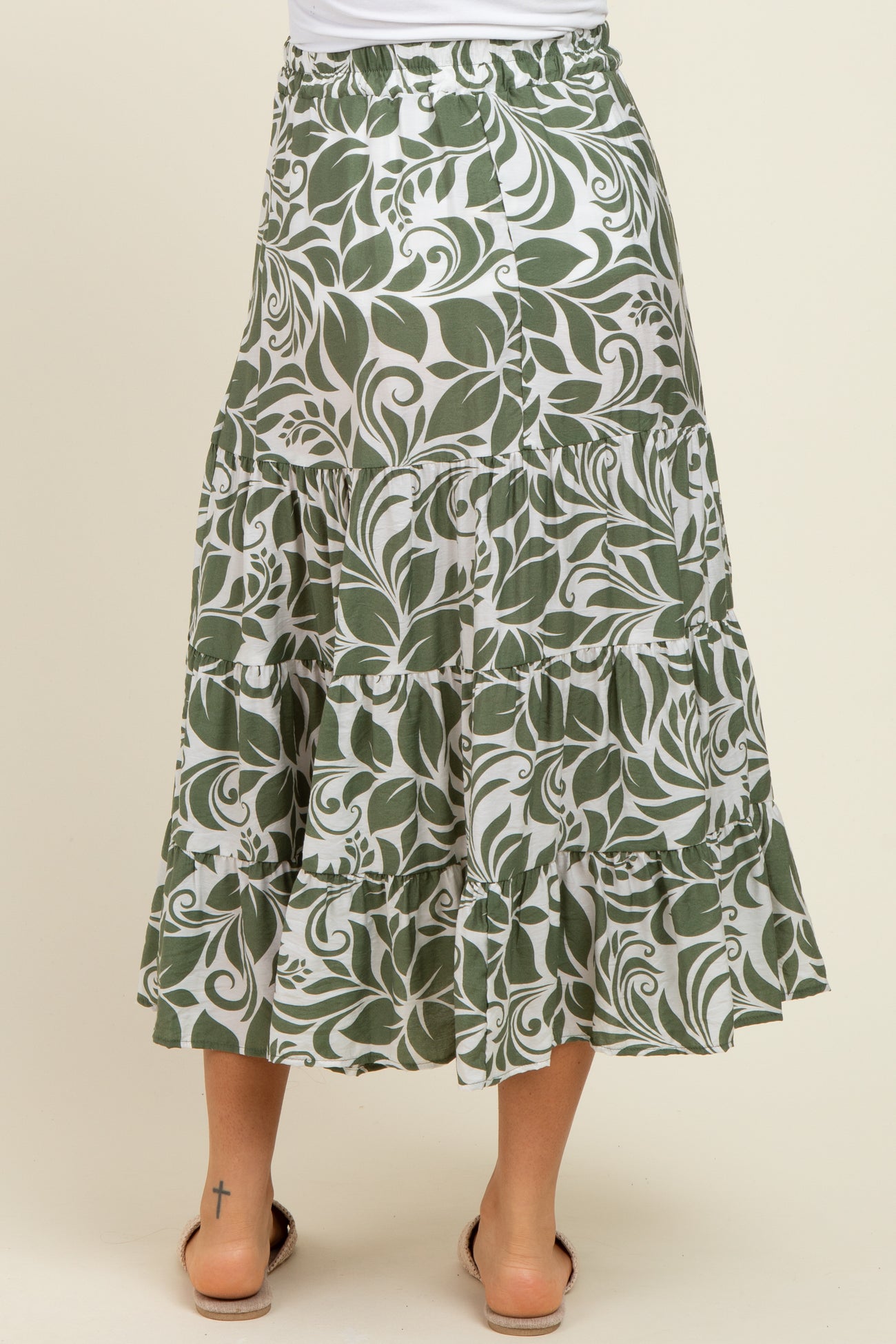 maternity wear featuring a green and white floral tiered maxi skirt with a relaxed fit. model standing with back facing the camera