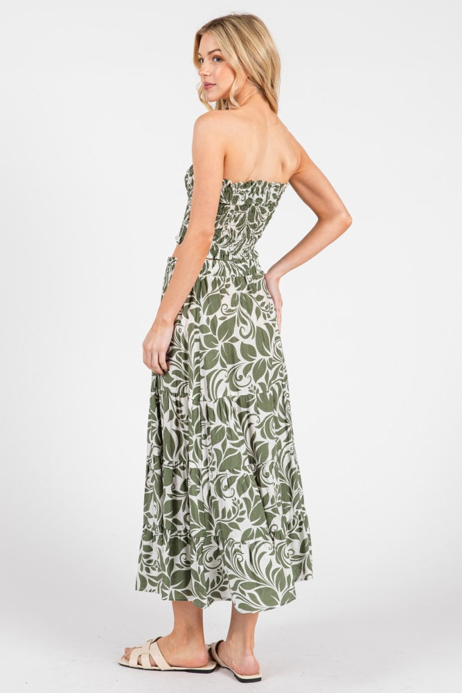 woman wearing a strapless green floral maxi dress, showing the back view and styled with flat sandals