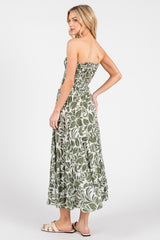 woman wearing a strapless green floral maxi dress, showing the back view and styled with flat sandals