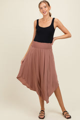 woman wearing a black tank top and a flowy mauve maternity skirt standing with one hand on her hip