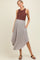 woman wearing a brown sleeveless top and a flowy gray maternity skirt with pockets