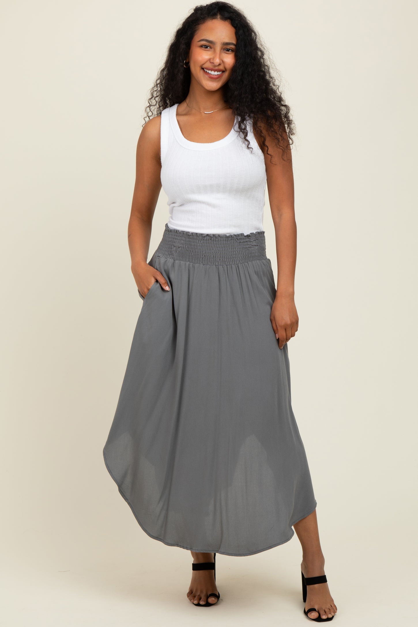 woman wearing a white tank top and a gray maxi skirt with a smocked waistband and side pockets