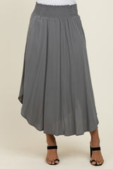 woman wearing a gray flowy midi skirt with a smocked waistband and an asymmetrical hemline