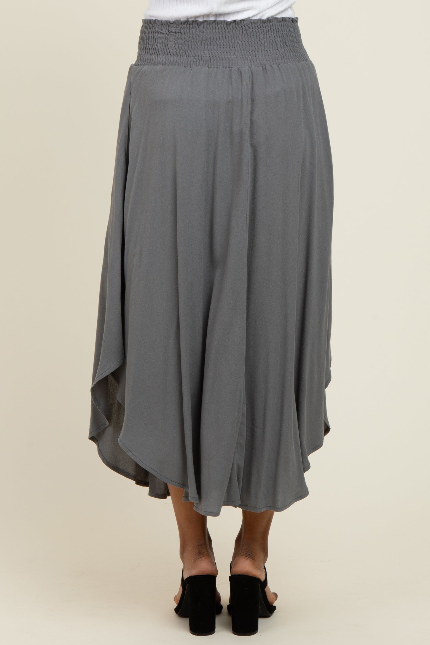 woman wearing a gray flowy midi skirt with a smocked waistband and asymmetrical hem