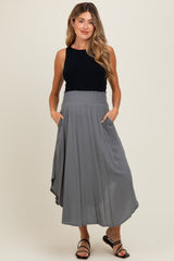 woman wearing a black sleeveless top and a flowy gray maternity skirt with side pockets