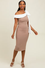woman wearing a fitted brown midi dress with an off-the-shoulder white bow detail and strappy white heels